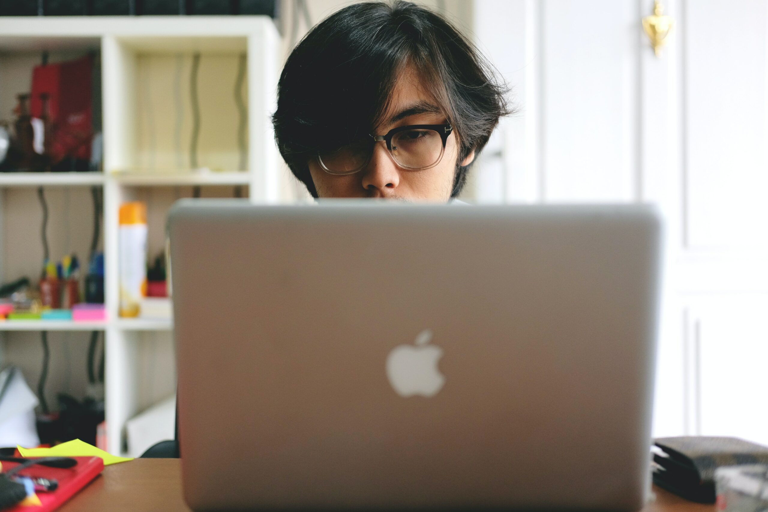a man sits at his macbook, looking at the screen