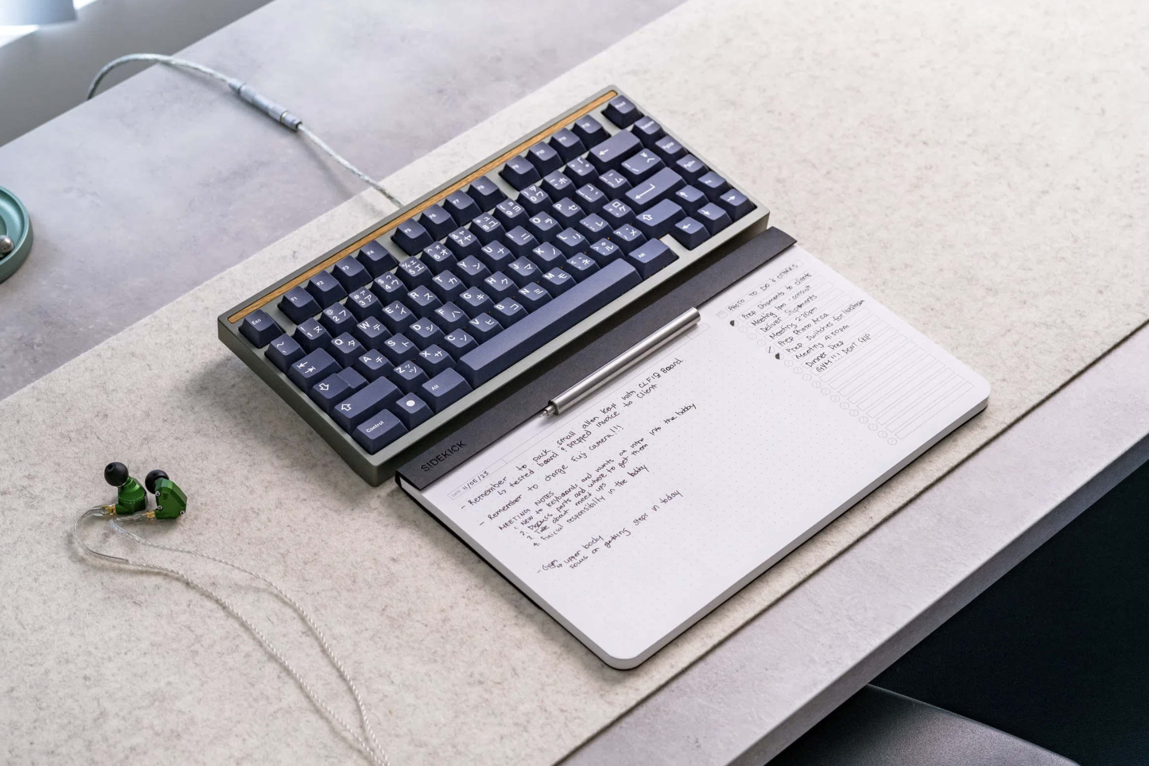 A white notebook sits on a desk underneath a mechanical keyboard. It's made up of a list on the right hand side and a dotted paper matrix on the the right.