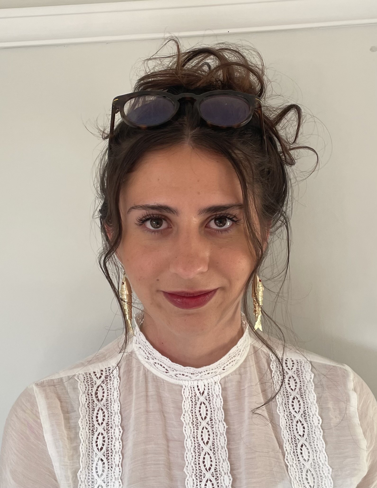 Olivia Griffin, a woman with dark brown hair that is tied up, looks to camera. She is wearing a white blouse.