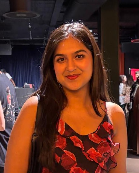 Saniya, a woman with long dark hair, looks to camera