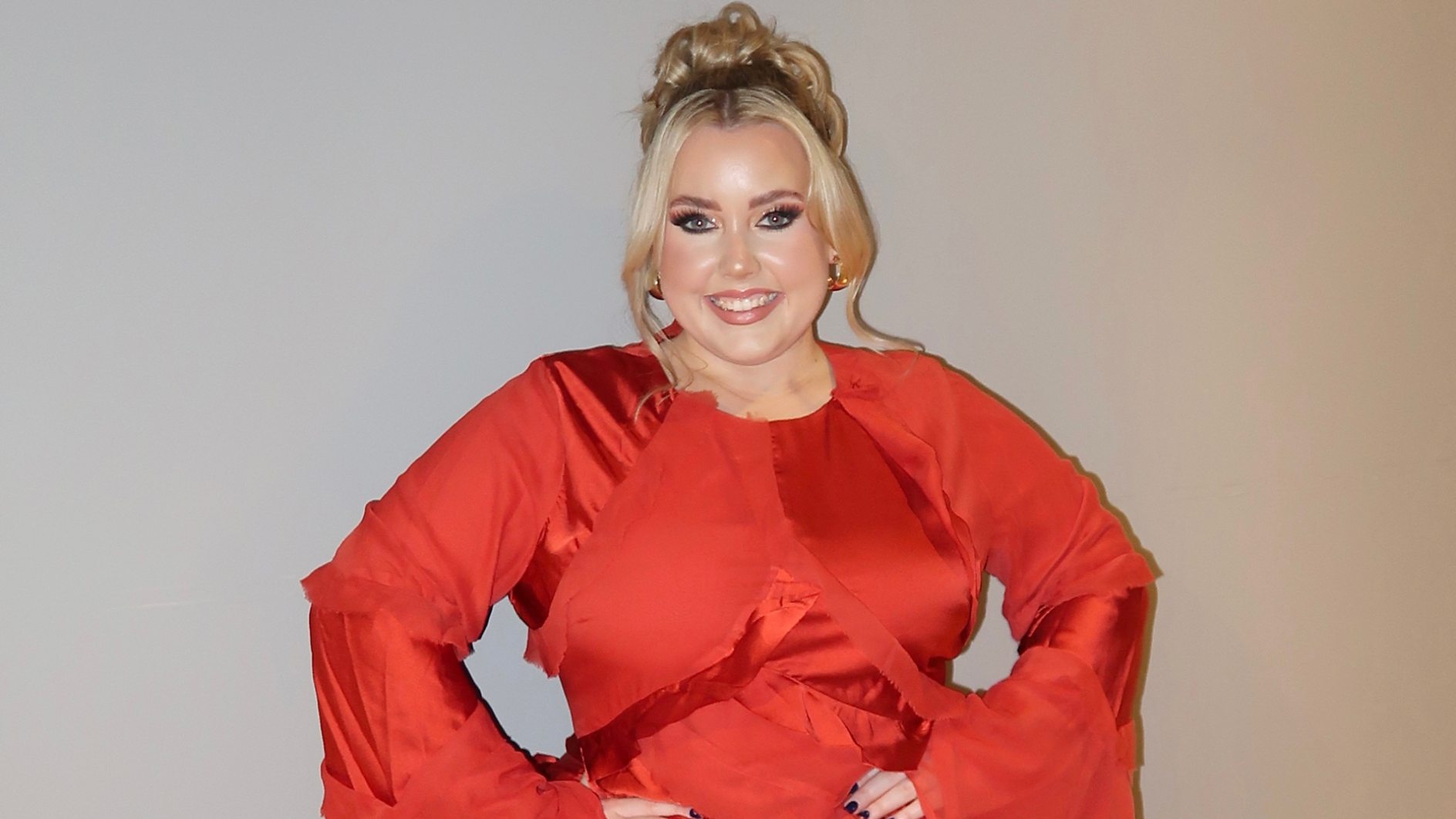 Charley Marlowe in a bright red dress, smiling to camera